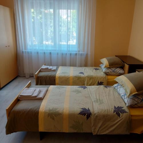 a room with three beds in front of a window at Асклепион in Kyustendil