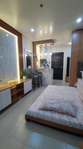 a bedroom with a large bed and a kitchen at Plumera Mactan near Airport in Bankal