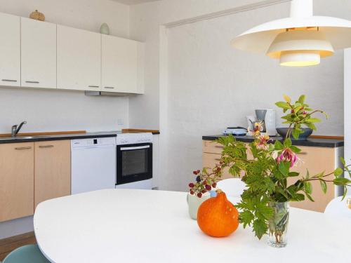 a kitchen with a white table with a vase of flowers at Apartment in Holiday park- free waterpark in Ulfborg