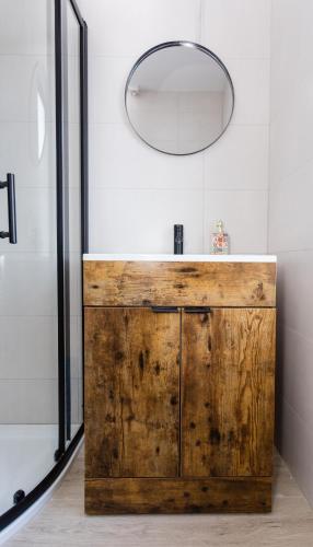 a bathroom with a wooden vanity and a mirror at Cosy Home Swinford Town in Swinford