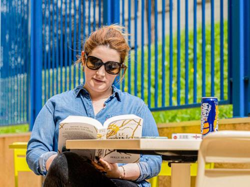 a woman sitting at a table reading a book at ibis budget Paris Porte d'Italie Ouest in Le Kremlin-Bicêtre