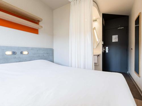 a bedroom with a white bed and a black door at ibis budget Paris Porte d'Italie Ouest in Le Kremlin-Bicêtre