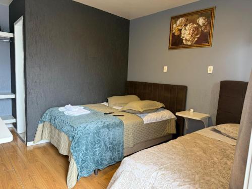 a bedroom with two beds and a picture on the wall at Pousada Nativa Lages in Lages