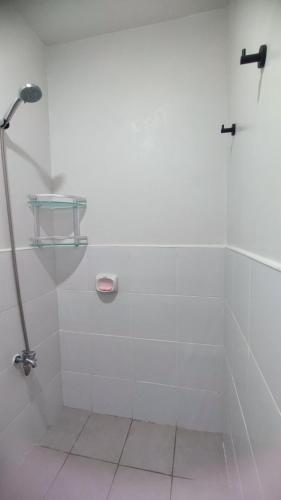 a white bathroom with a shower with a glass shelf at Plumera Mactan near Airport in Bankal