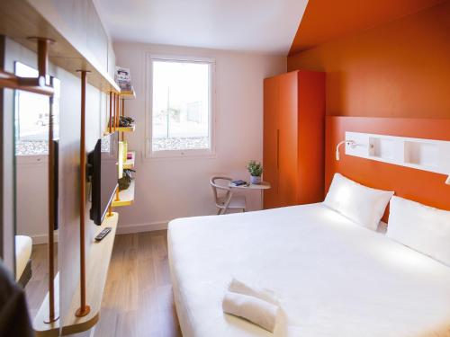 a bedroom with a white bed and an orange wall at ibis budget Cherbourg - La Glacerie in Cherbourg en Cotentin