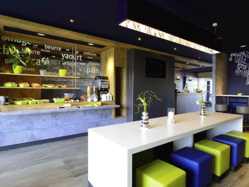 a restaurant with a counter with colorful stools at ibis budget Cherbourg - La Glacerie in Cherbourg en Cotentin