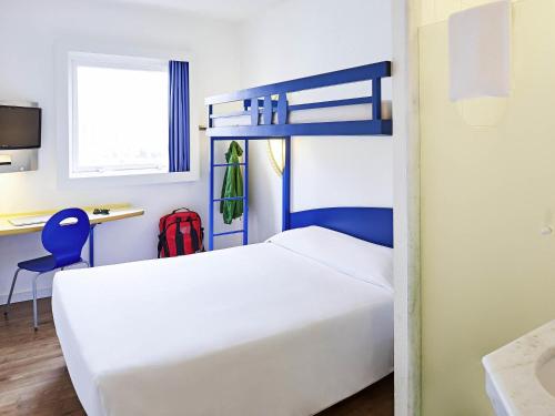a bedroom with a white bed and a desk with a red backpack at ibis budget Curitiba Centro in Curitiba