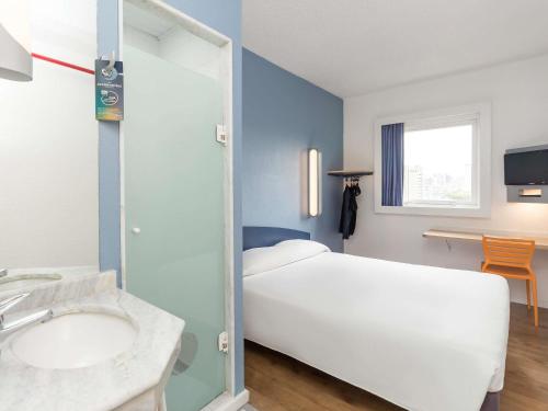 a bedroom with a white bed and a sink at ibis budget Curitiba Centro in Curitiba