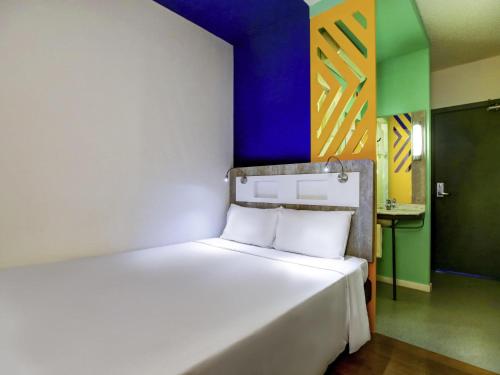 a bedroom with a white bed with a colorful wall at ibis budget Tambore in Barueri