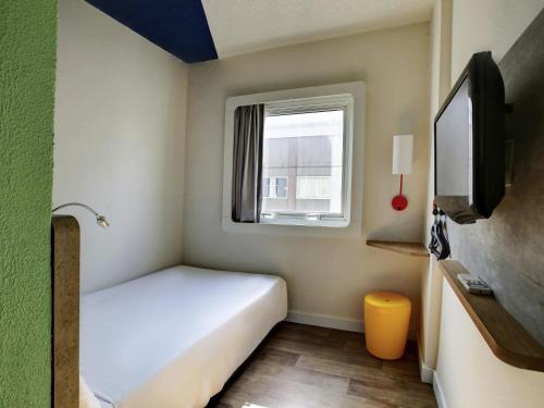 a small room with a bed and a window at ibis budget Tambore in Barueri