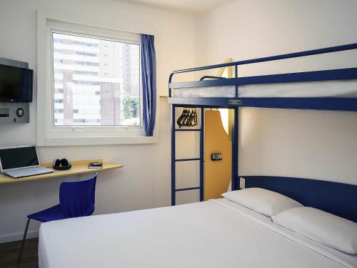 a bedroom with a bunk bed and a desk with a laptop at ibis budget Sao Paulo Morumbi in Sao Paulo