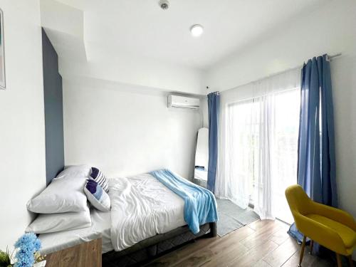 a bedroom with a bed and a yellow chair at The Coastal Cove - One Bedroom in Iloilo City