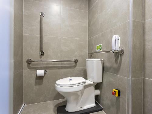 a bathroom with a toilet and a phone on the wall at ibis budget Sao Paulo Jardins in Sao Paulo
