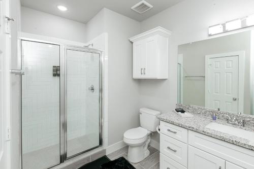 a white bathroom with a shower and a toilet at Luxury 3BR Getaway Near Downtown - Med Center - NRG - Enjoy Smart TVs - Fast WiFi - Private Backyard in Houston