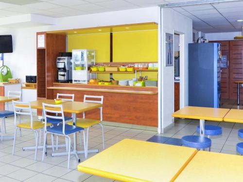 a restaurant with tables and chairs and a kitchen at ibis budget Nevers Varennes Vauzelles in Varennes Vauzelles