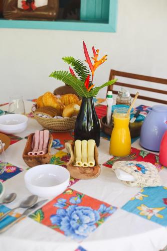 a table with food and a vase with a plant on it at Casa Peroá Pousada in Icaraí