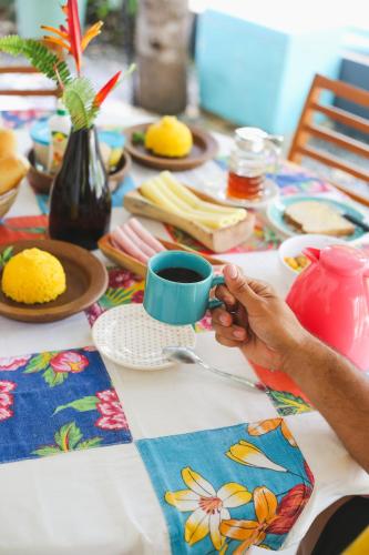 a person holding a cup of coffee on a table at Casa Peroá Pousada in Icaraí
