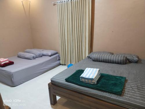 Un dormitorio con dos camas y una ventana. en Station house ijen, en Banyuwangi