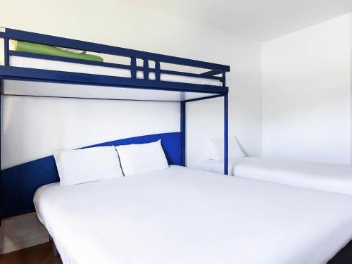 a bedroom with two bunk beds with white sheets at Ibis Budget Agen in Le Passage