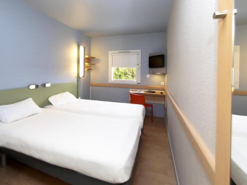 a hotel room with a large bed and a desk at Ibis Budget Dole-Choisey in Dole
