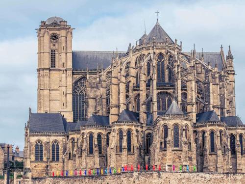 a large stone cathedral with a clock tower at ibis budget Le Mans Centre in Le Mans