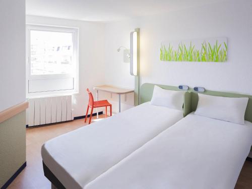 a bedroom with two beds and a table and a window at ibis budget Limoges Centre Gare in Limoges