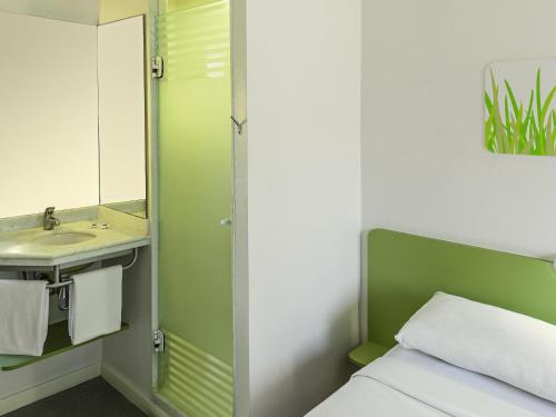 a bathroom with a bed and a sink and a mirror at ibis budget Belo Horizonte Minascentro in Belo Horizonte