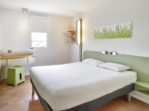 a bedroom with a large white bed and a desk at ibis budget Bergerac in Bergerac