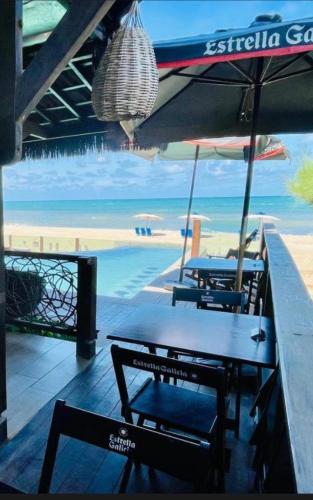 a table with chairs and an umbrella on a beach at Pousada Maracabana Spa in Porto De Galinhas