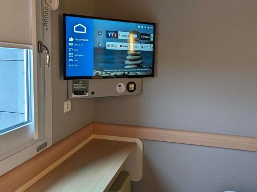 a flat screen tv on the wall of a room at ibis budget Saint-Omer Centre in Saint-Omer