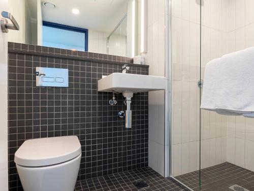a bathroom with a toilet and a sink at ibis budget Sydney Airport in Sydney