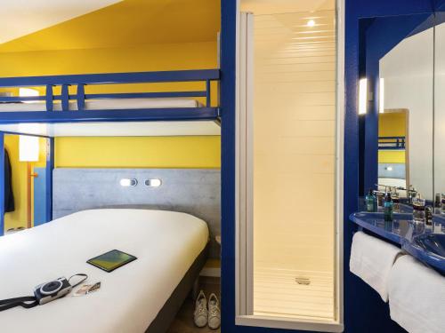 a room with a bed and a bathroom with bunk beds at ibis budget Nuits Saint Georges in Nuits-Saint-Georges