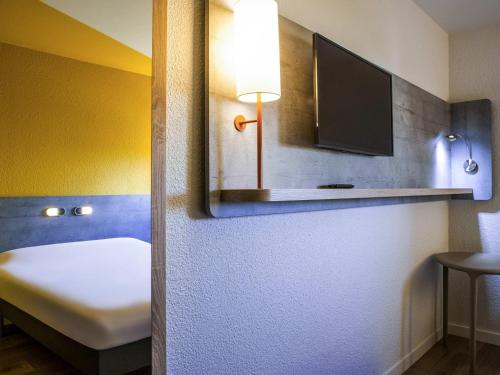 a room with a bed and a tv on a wall at ibis budget Nuits Saint Georges in Nuits-Saint-Georges