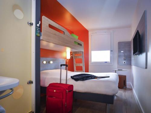 a hotel room with a bed and a red suitcase at ibis budget Saint Lô in Saint Lo