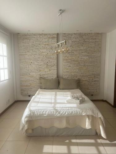a bedroom with a large white bed with a brick wall at Pousada Jupter in Teresópolis