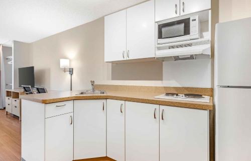 a kitchen with white cabinets and a microwave at Extended Stay America Suites - San Diego - Carlsbad Village by the Sea in Carlsbad