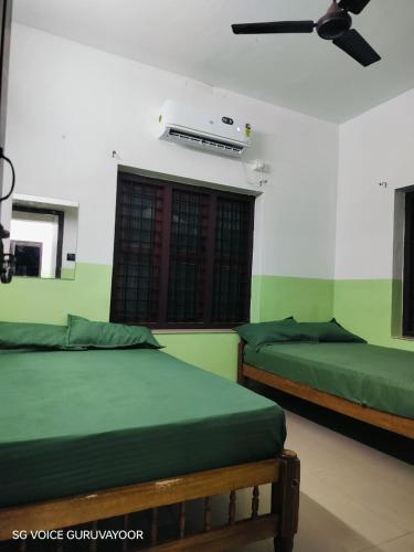 two beds in a room with green walls at Clap House Home in Guruvāyūr