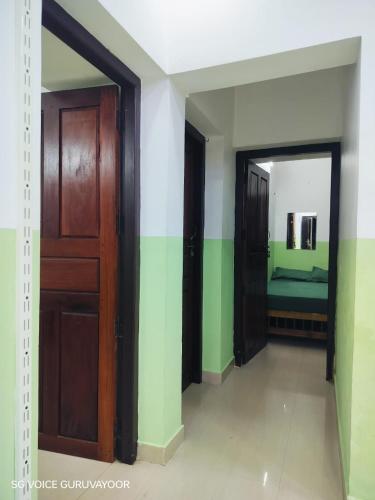 a hallway with a door and a bed in a room at Clap House Home in Guruvāyūr