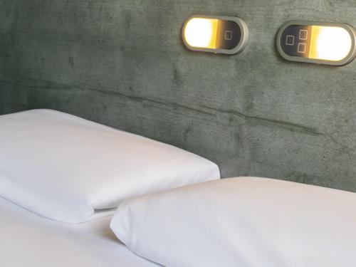 a bedroom with two beds and two clocks on the wall at ibis budget Meudon Paris Ouest in Meudon