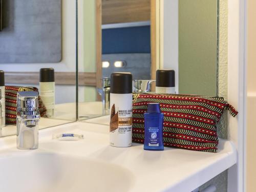 a bathroom counter with some products on a sink at ibis budget Meudon Paris Ouest in Meudon