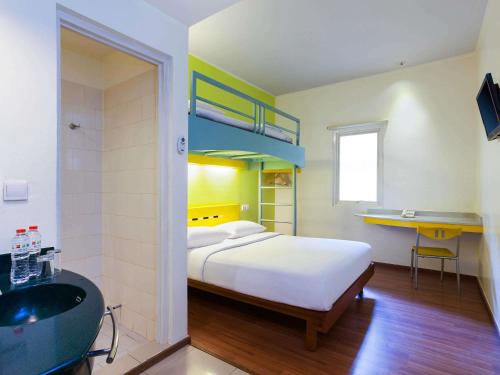 a bedroom with a bed and a bathroom with a sink at Ibis Budget Jakarta Menteng in Jakarta