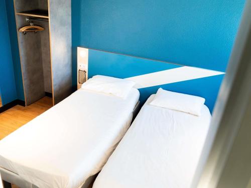 two beds in a room with a blue wall at ibis budget Aix en Provence in Aix-en-Provence