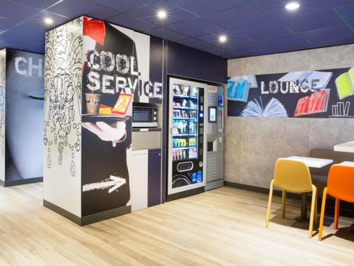 a restaurant with a cooler and a table and chairs at ibis budget Thonon Les Bains in Thonon-les-Bains