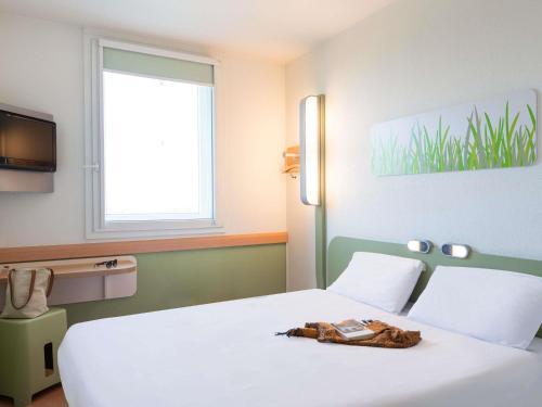a bedroom with a white bed and a window at ibis budget Bordeaux Sud in Villenave-dʼOrnon