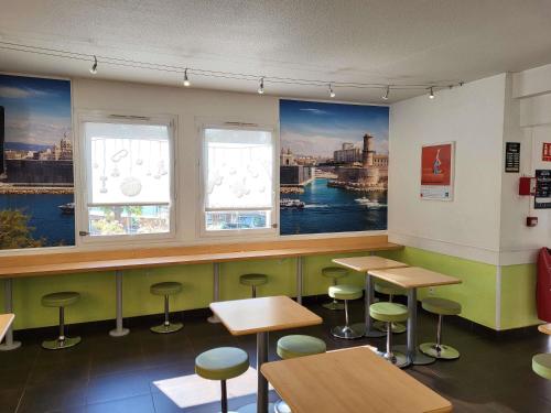 a restaurant with tables and stools and windows at Ibis Budget Marseille Valentine in Marseille