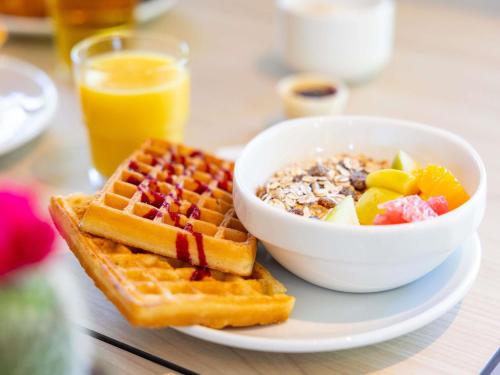 a plate of waffles and a bowl of cereal and a bowl of fruit at ibis budget Bourg en Bresse in Bourg-en-Bresse