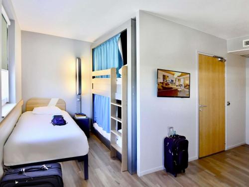 une chambre d'hôtel avec un lit et deux valises dans l'établissement Ibis Budget Nantes Rezé Aéroport, à Rezé