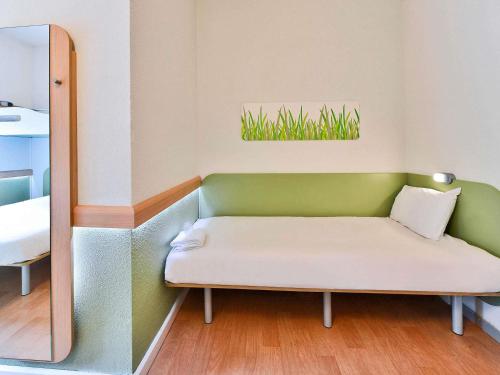a couch in a room with a mirror at Ibis Budget Grenoble Sud Seyssins in Seyssins