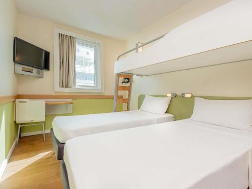 a hotel room with two beds and a tv at ibis budget Vitoria in Vitória