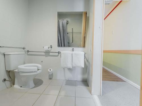a bathroom with a toilet and a mirror and towels at ibis budget Vitoria in Vitória